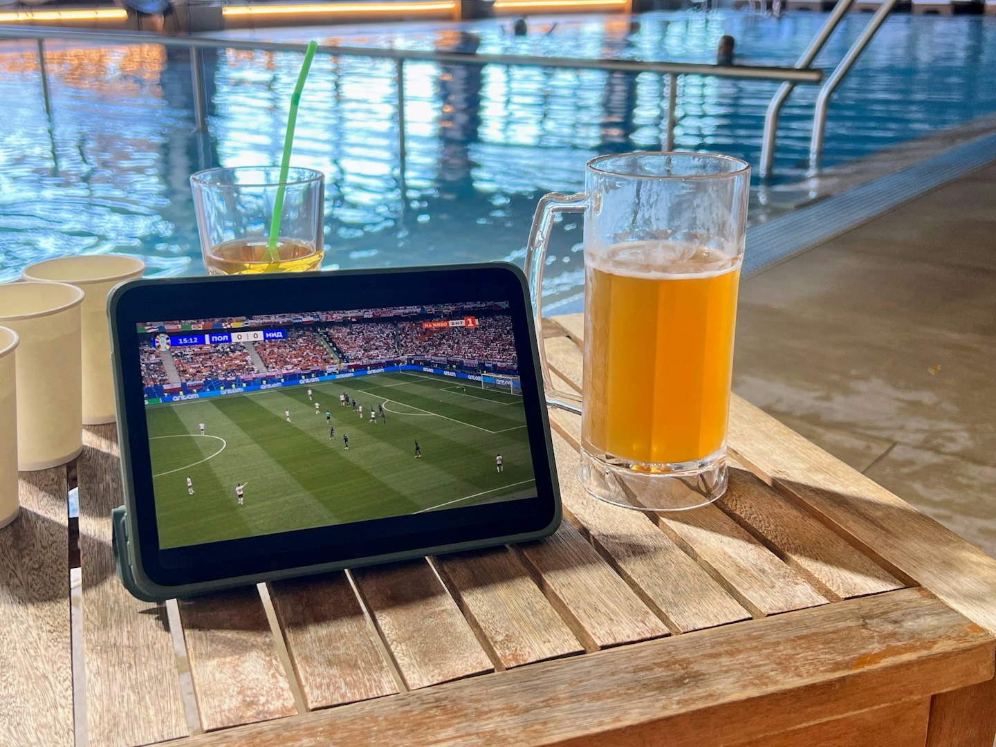A tablet showing a soccer game sits on a wooden table.